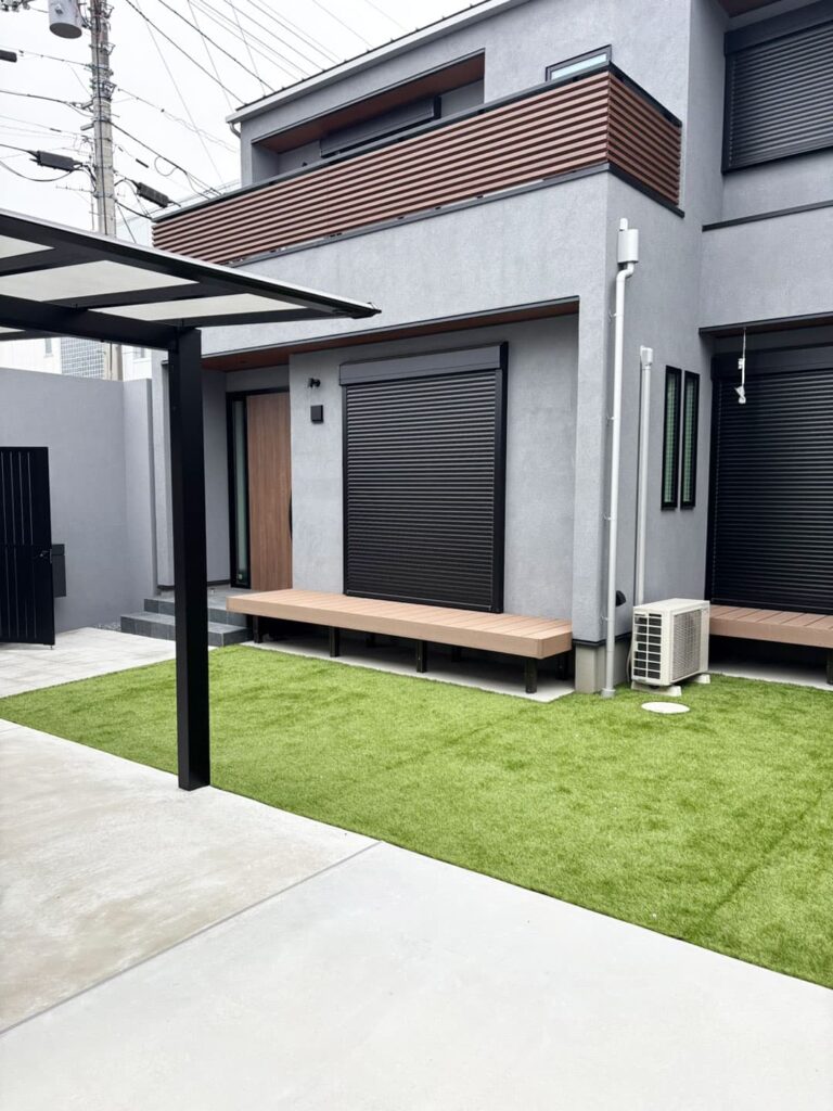 シックでモダンな住宅の前に広がるウッドデッキと芝生の庭