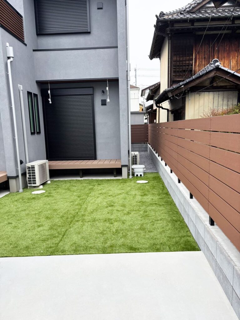 ウッドデッキと芝生の庭、境界にはウッド調の目隠しフェンス